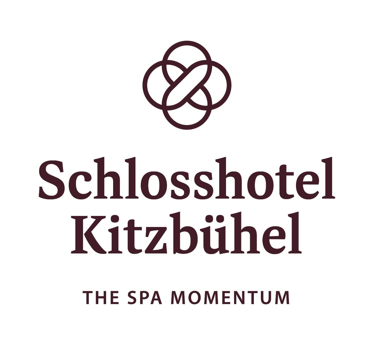 A logo of the Schloss Hotel Kitzbühel with the slogan "THE SPA MOMENTUM". It conveys an elegant and luxurious impression.