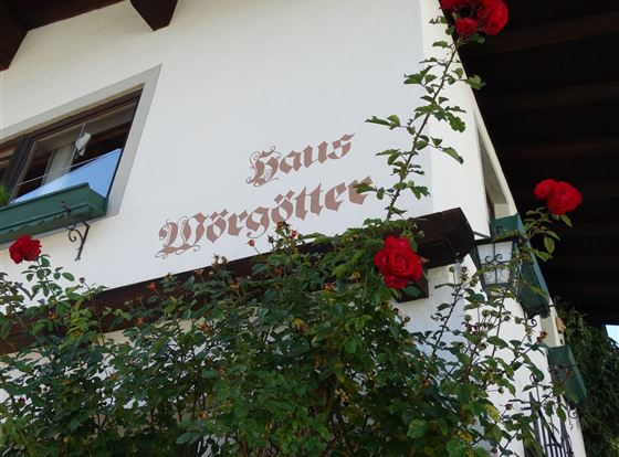 Ein altes Gebäude mit der Aufschrift "Haus Möggötter". Rote Rosen ranken an der Wand und verleihen dem Bild einen charmanten Charakter.