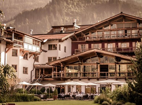Ein charmantes Hotel in den Bergen mit einer einladenden Terrasse. Wunderschöne Natur umgibt die Gebäude.
