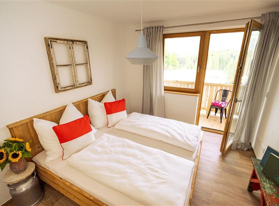 Ein gemütliches Zimmer mit zwei Einzelbetten und einer hellen Farbgestaltung. Vom Balkon aus bietet sich ein schöner Ausblick ins Freie.