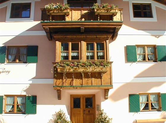 Ein schönes, dreigeschossiges Haus mit einem Holzbalkon und grünen Fensterläden. Der Schnee bedeckt den Boden und verleiht der Szene eine winterliche Atmosphäre.