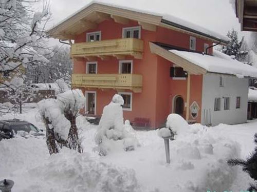 Ein schneebedecktes Haus in einer winterlichen Umgebung. Der Schnee liegt hoch und die Balkone sind gut sichtbar.