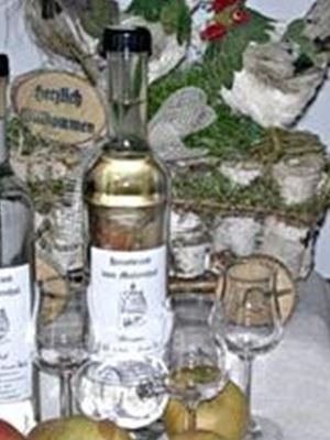 Zwei Flaschen Apfelgeist stehen neben Gläsern und frischen Äpfeln auf einem Tisch. Im Hintergrund sind ländliche Dekorationen zu sehen.