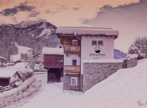 Ein malerisches, schneebedecktes Gebäude in den Alpen. Im Hintergrund sind majestätische Berge zu sehen.