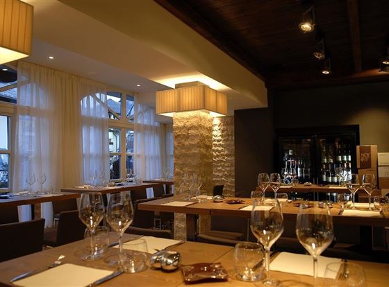 Ein stilvolles Restaurant mit eleganten Tischen und Gläsern. Sanftes Licht und moderne Einrichtung schaffen eine einladende Atmosphäre.