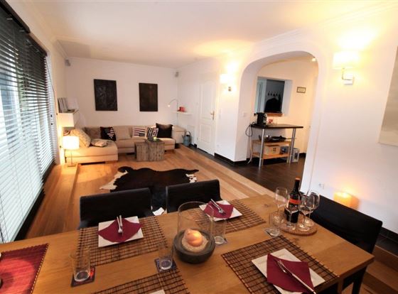 Ein modernes Wohnzimmer mit einem gemütlichen Sofa und einem Holzboden. Der Essbereich ist elegant gedeckt und strahlt eine einladende Atmosphäre aus.
