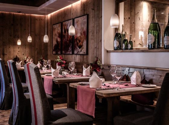 Ein stilvolles Restaurant mit Holzdekor und sanfter Beleuchtung. Tische sind elegant gedeckt mit Blumen und Gläsern.