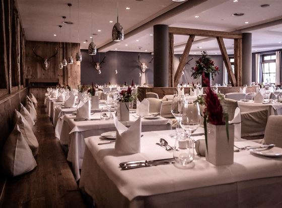 Ein elegantes Restaurant mit geschmackvoll gedeckten Tischen. Die Einrichtung kombiniert Holz und moderne Elemente, ideal für besondere Anlässe.