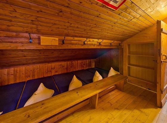 Ein gemütlicher Raum mit Holzverkleidung und Bänken. Er bietet Platz zum Entspannen und hat ein warmes, einladendes Ambiente.