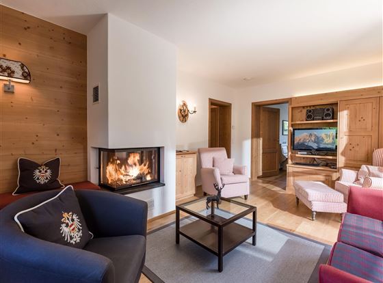 Ein modernes Wohnzimmer mit einem gemütlichen Kamin und komfortablen Möbeln. Die warmen Holzdetails schaffen eine einladende Atmosphäre.