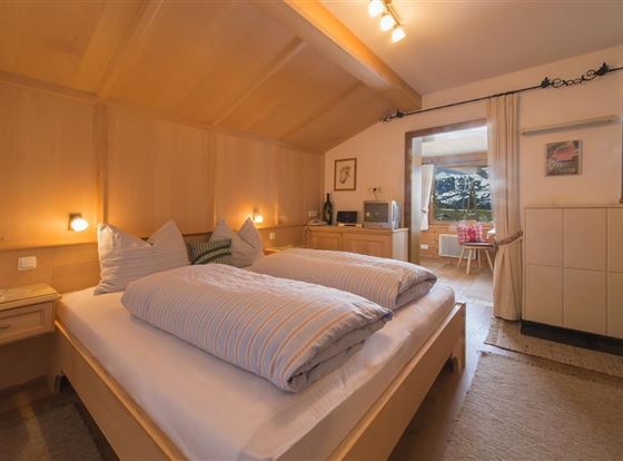 Ein gemütliches Schlafzimmer mit zwei Einzelbetten und Holzverkleidung. Das Zimmer hat eine helle Atmosphäre und einen Blick auf den Balkon.