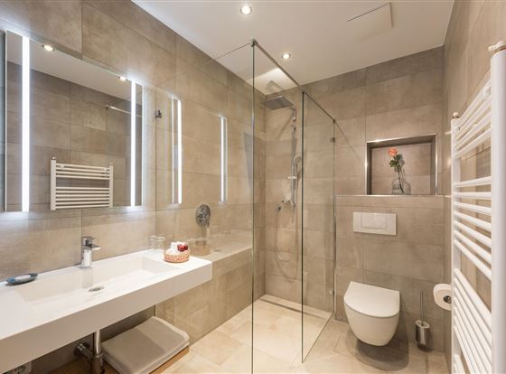 Ein modernes Badezimmer mit einer transparenten Dusche und eleganten Fliesen. Der Raum ist hell und hat eine schlichte, stilvolle Ausstattung.