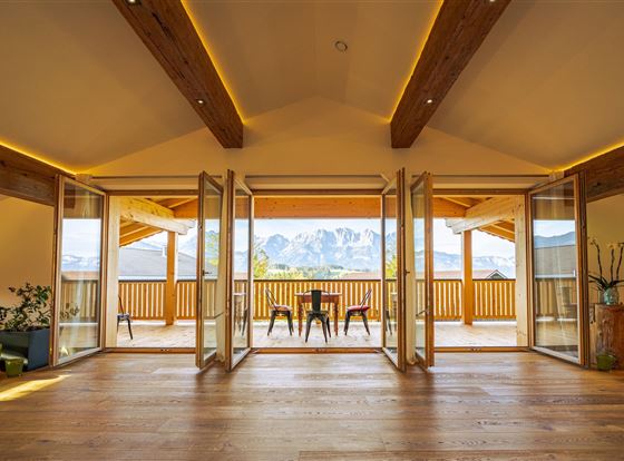 Eine moderne Wohnung mit offenem Raum und großen Fenstern. Von der Terrasse hat man einen schönen Blick auf die Berge.