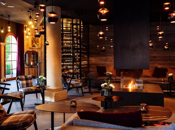 A cozy interior with stylish furniture and soft lighting. The room features a fireplace and a wine collection.