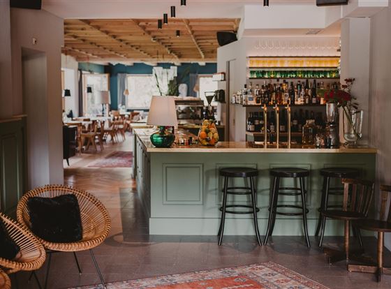 Ein stilvolles Café mit einer einladenden Bar und modernen Möbeln. Der Raum ist hell und freundlich gestaltet, ideal für entspannte Treffen.