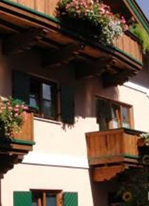 Ein traditionelles Gebäude mit Blumenkästen und Holzverzierungen. Die Fensterläden sind grün, und die Fassade ist hell gefärbt.