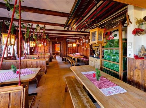 Ein gemütliches Restaurant mit Holzmöbeln und rustikalem Dekor. Auf den Tischen sind gestreifte Tischdecken und kleine Pflanzen dekoriert.