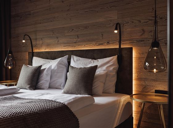 Ein modernes Schlafzimmer mit einem großen Bett und sanften Beleuchtung. Die Wände sind aus Holz, und die Dekoration ist stilvoll und gemütlich.