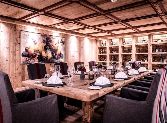 Ein elegantes Esszimmer mit einem großen Holztisch und gemütlichen Stühlen. Die Wände sind aus Holz, und ein Kunstwerk ziert die Wand im Hintergrund.