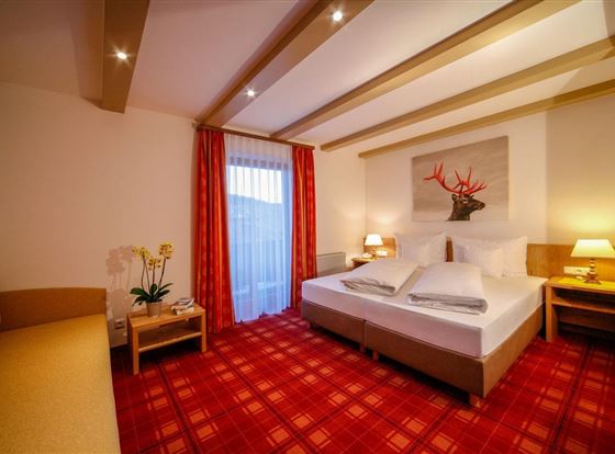 Ein gemütliches Schlafzimmer mit einem großen, bequemen Bett und einem Sofa. Die warmen Farben und das Dekor schaffen eine einladende Atmosphäre.