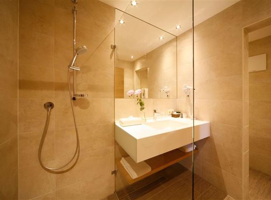 Ein modernes Badezimmer mit einer Dusche und einem eleganten Waschbecken. Die Wände sind hell und der Raum wirkt sauber und einladend.