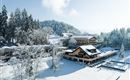 Ein malerisches Winterdorf mit schnee bedeckten Bergen und ruhigen Wäldern. Die Gebäude sind inmitten einer idyllischen Schneelandschaft gelegen.
