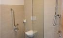 Ein modernes Badezimmer mit einer Dusche und einer Toilette. Die Wände sind hell gefliest, und der Boden ist aus braunen Fliesen.