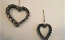 Zwei hängende Herzdekorationen aus Holz, die an einer Wand befestigt sind. Die Herzen sind aus dunklen Holzscheiben gefertigt und verleihen einen rustikalen Charme.