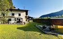 Ein schönes Haus mit einem gepflegten Garten und Blick auf die Berge. Die Umgebung ist grün und einladend, ideal zum Entspannen.