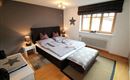 Ein gemütliches Schlafzimmer mit einem großen Bett und dekorativen Kissen. Helle Wände und ein Fenster sorgen für eine freundliche Atmosphäre.