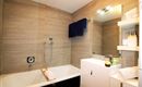 Ein modernes Badezimmer mit einer Badewanne und einer eleganten Waschbecken-Anlage. Die Wände sind in warmen Farbtönen gestaltet und es sind Handtücher und Toilettenartikel sichtbar.