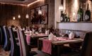 Ein stilvolles Restaurant mit Holzdekor und sanfter Beleuchtung. Tische sind elegant gedeckt mit Blumen und Gläsern.