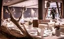 Ein elegantes Restaurant mit gedeckten Tischen und modernen Lichtinstallationen. Die Atmosphäre ist gemütlich und einladend.