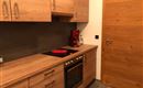 Eine moderne Küche mit Holzmöbeln und eleganten Geräten. Es gibt einen Herd, einen Backofen und eine Kaffeemaschine in einem gut gestalteten Raum.