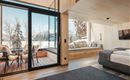 Ein modernes Zimmer mit Holzdekor und großen Fenstern. Draußen sieht man eine winterliche Berglandschaft.