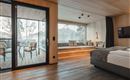 Ein modernes Hotelzimmer mit einem großen Fenster und Blick auf einen Balkon. Der Raum ist mit Holz und neutralen Farben eingerichtet und wirkt einladend.