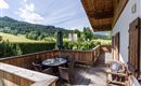 Ein schöner Balkon mit Blick auf die grünen Hügel. Ein Tisch mit Stühlen lädt zum Entspannen ein.