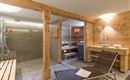 Ein moderner Wellnessbereich mit einer Sauna und einer Dusche. Holzverkleidungen und entspannende Liegen sorgen für eine gemütliche Atmosphäre.