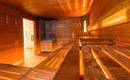 Eine gemütliche Sauna mit Holzverkleidung und gedämpftem Licht. Die Bank zum Sitzen lädt zum Entspannen ein.
