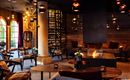 A cozy interior with stylish furniture and soft lighting. The room features a fireplace and a wine collection.
