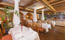 Ein gemütliches Restaurant mit Holzdekor und elegant eingedeckten Tischen. Die Atmosphäre ist warm und einladend.