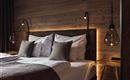 Ein modernes Schlafzimmer mit einem großen Bett und sanften Beleuchtung. Die Wände sind aus Holz, und die Dekoration ist stilvoll und gemütlich.