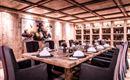 Ein elegantes Esszimmer mit einem großen Holztisch und gemütlichen Stühlen. Die Wände sind aus Holz, und ein Kunstwerk ziert die Wand im Hintergrund.